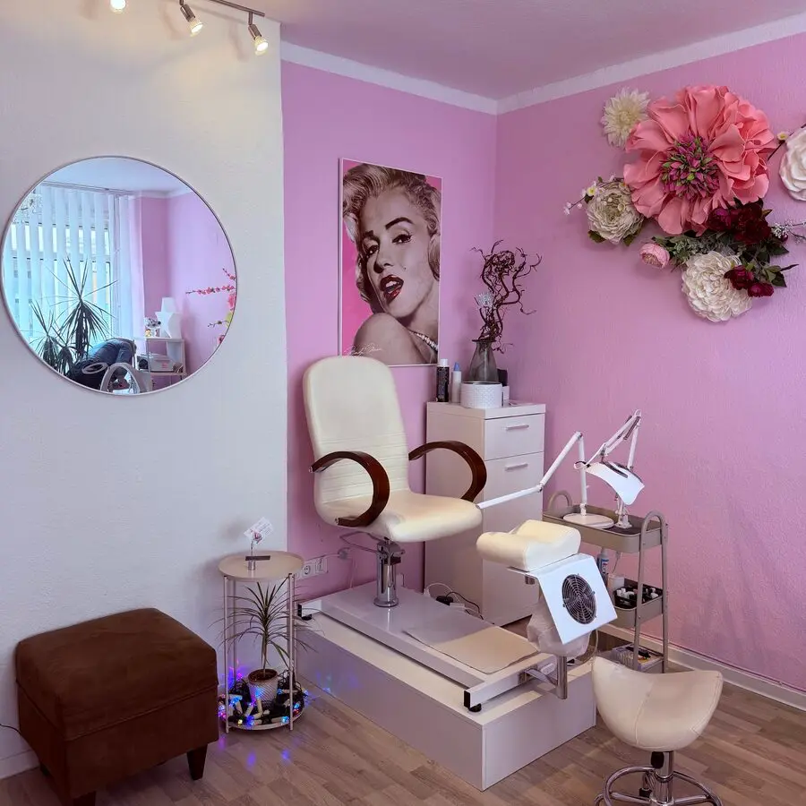 Pediküre-Stuhl und Arbeitsplatz vor rosa Wand mit Blumen